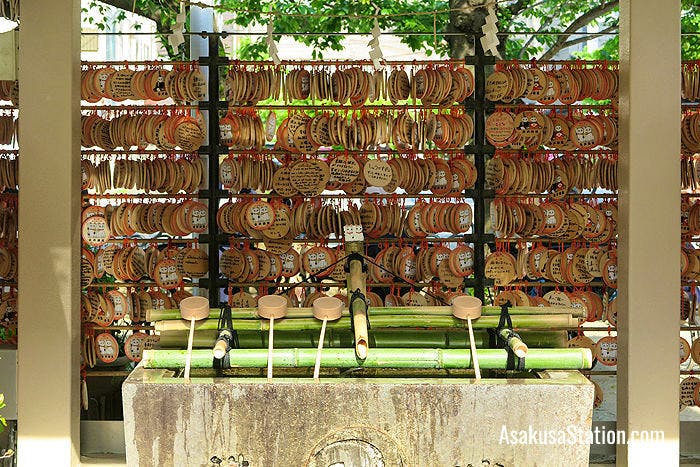 A basin for ritual washing surrounded by ema prayer plaques, at Imado Jinja