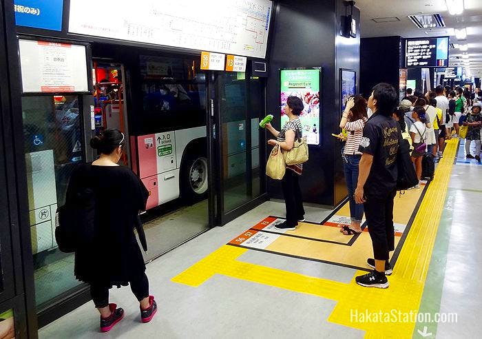 Passengers check bus departure times on the first floor of the Hakata Bus Terminal